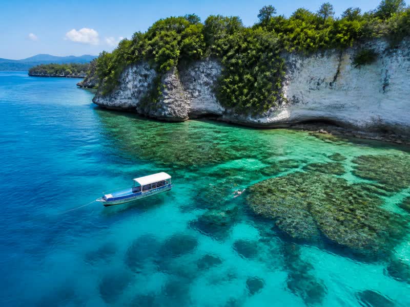 Clear turquoise water and coral reef beside the limestone cliffs of Menjangan Island